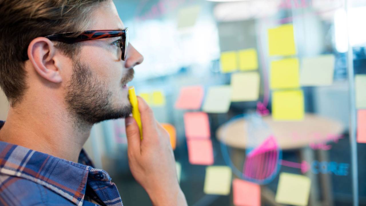 Imagem mostra homem branco de óculos olhando post-its