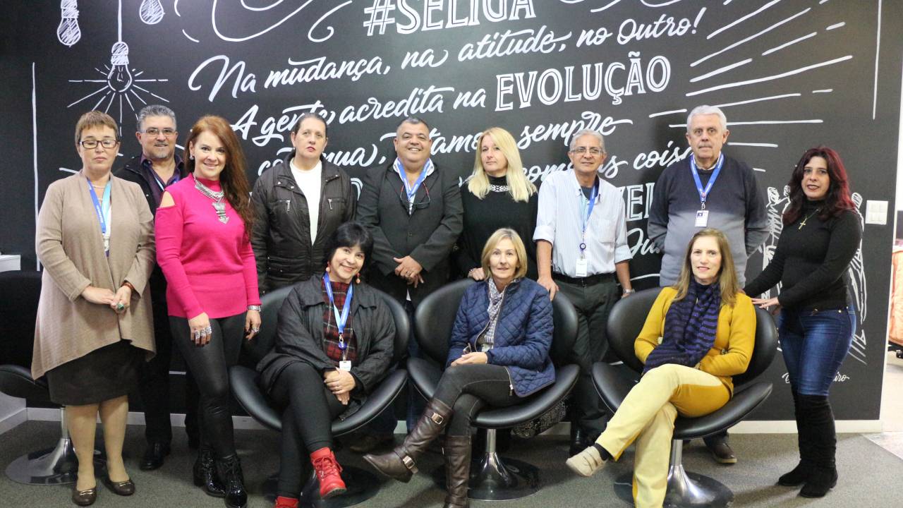 Funcionários com mais de 45 nos da Votorantim posam em frente a um mural para a foto