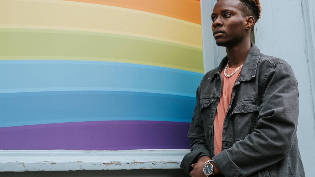 Jovem negro ao lado de uma bandeira LGBT+