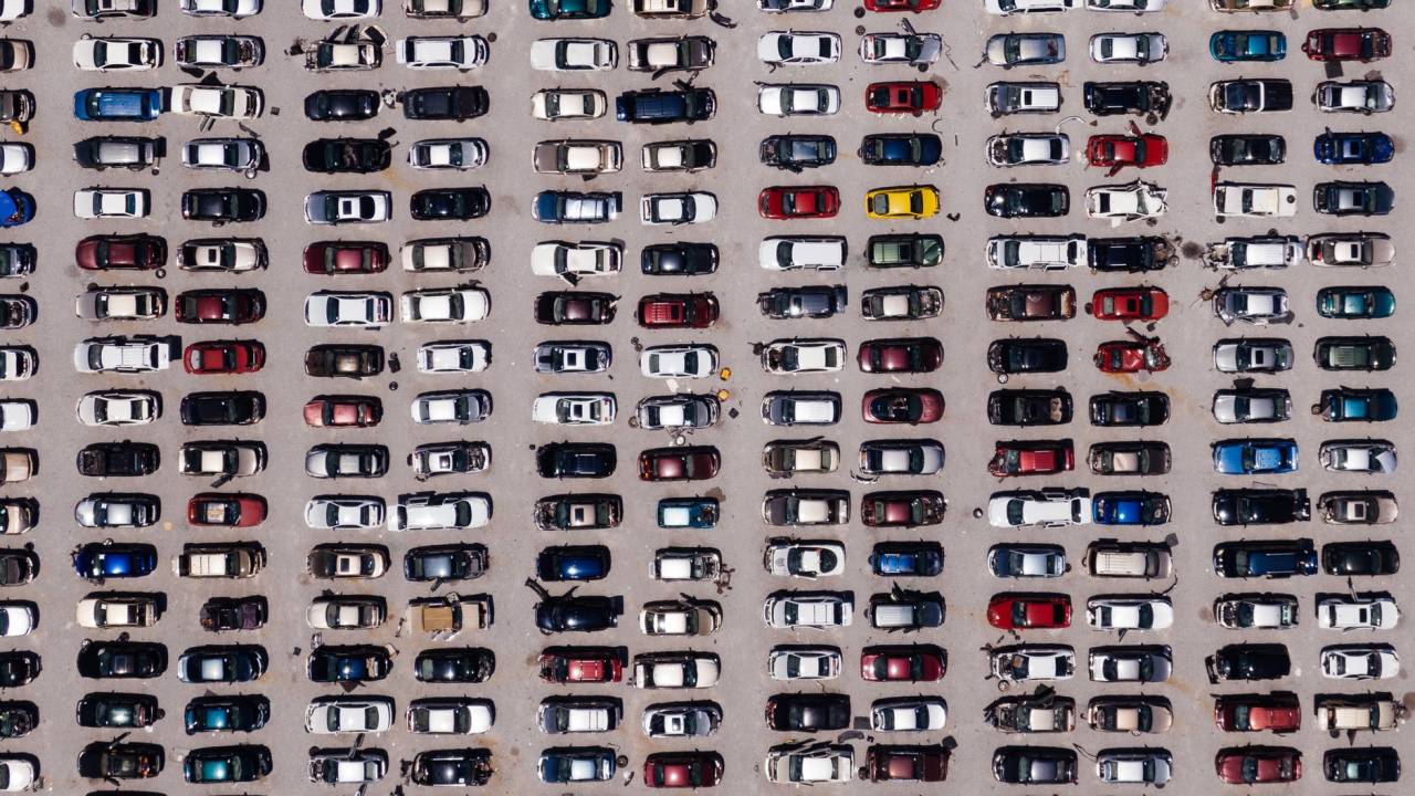 Imagem mostra um espaço aberto com vários carros estacionados visto de cima