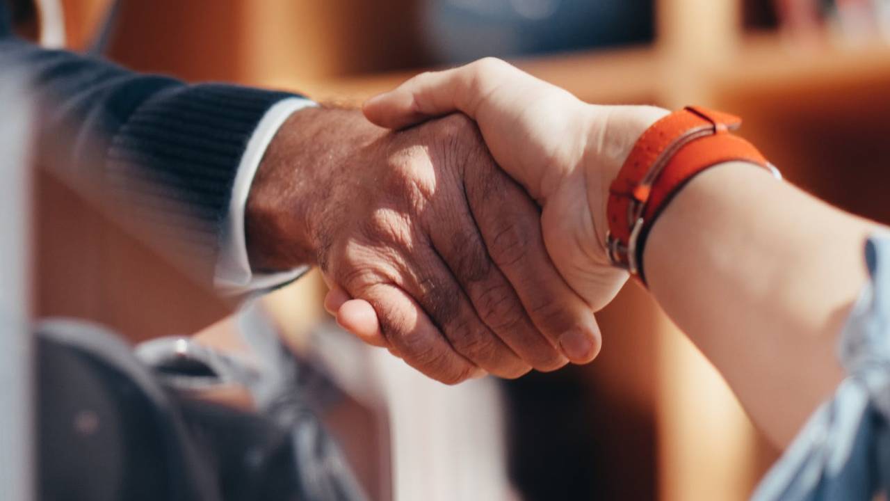 Imagem mostra duas pessoas dando um aperto de mãos, como se estivessem firmando um contrato
