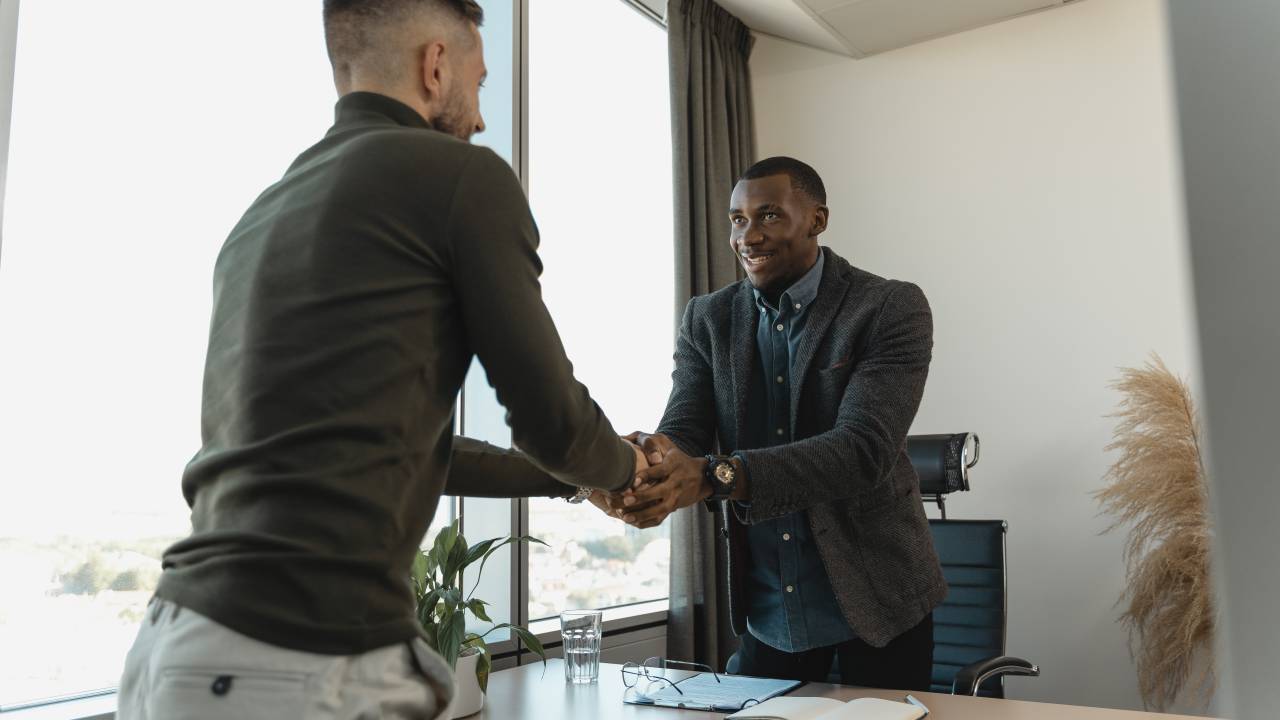 Dois homens se cumprimentam com um aperto de mão, como se estivessem firmando um compromisso