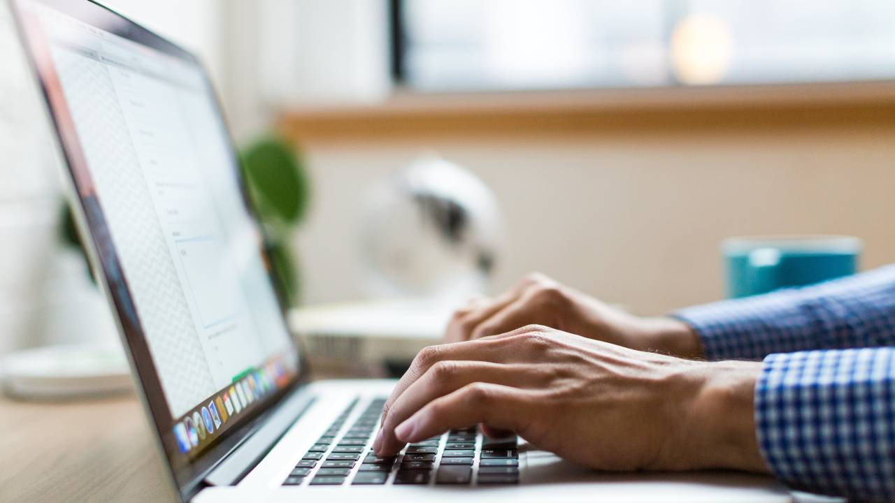 Homem digita ao teclado de um notebook
