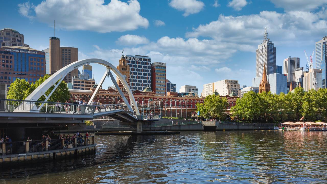 Imagem mostra uma ponte sobre águas na Austrália, em um dia ensolarado. Ao fundo, a Victoria University