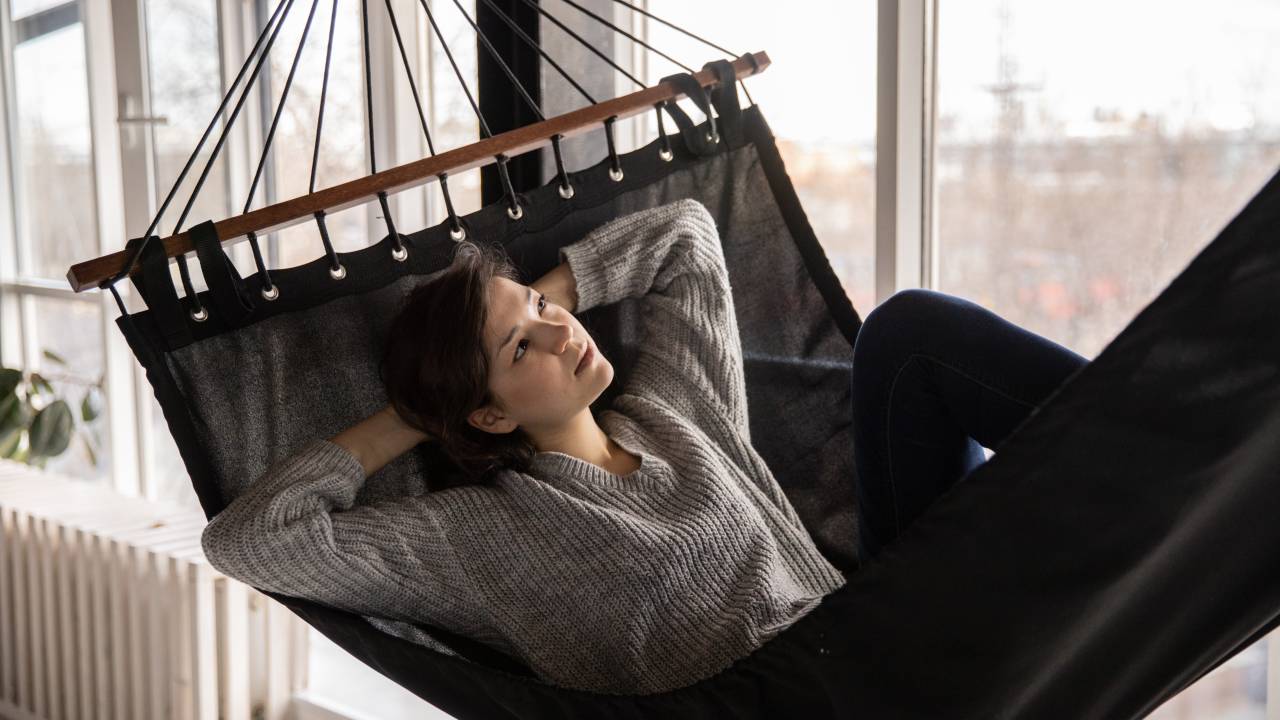 Mulher contempla o horizonte deitada em uma rede