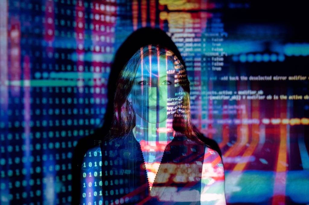 Imagem mostra sobreposição de rosto de mulher com códigos de computador